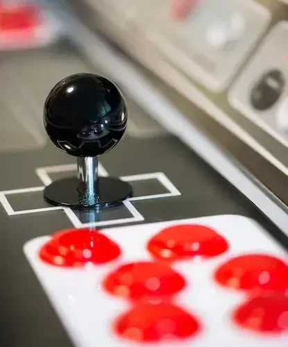 Close up of arcade machine joystick and illuminated action buttons
