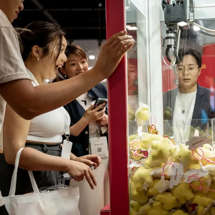Attendees playing a branded claw machine filled with plush prizes at a corporate event.