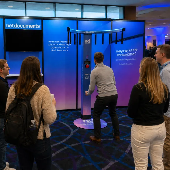 Netdocuments branded reaction game at a trade show booth with attendees watching a player.