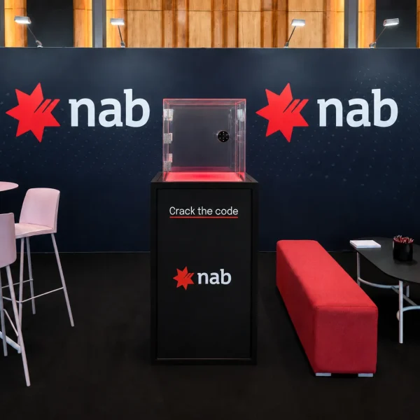 NAB branded prize safe activation with clear acrylic code safe on a branded plinth inside a corporate event stand.